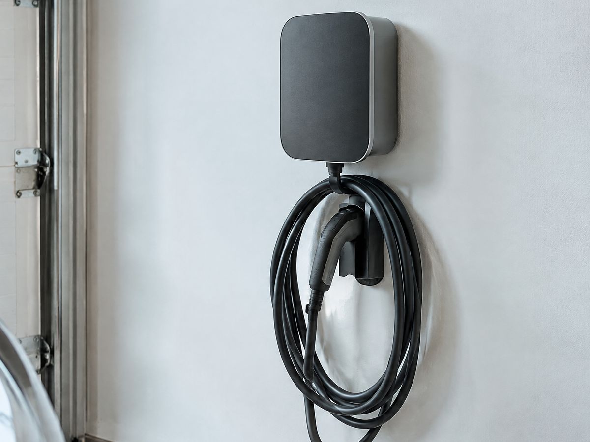Laadpaal aan een gevel met aangesloten elektrische wagen